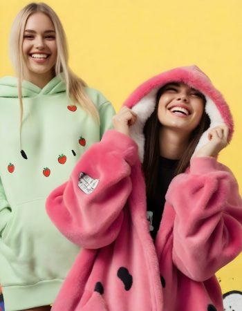 Two women , both Caucasian around 25 years old both wearing a thick fur oversized hoodie with food print, with white fur lining, both smiling, against a  graffiti background (11)